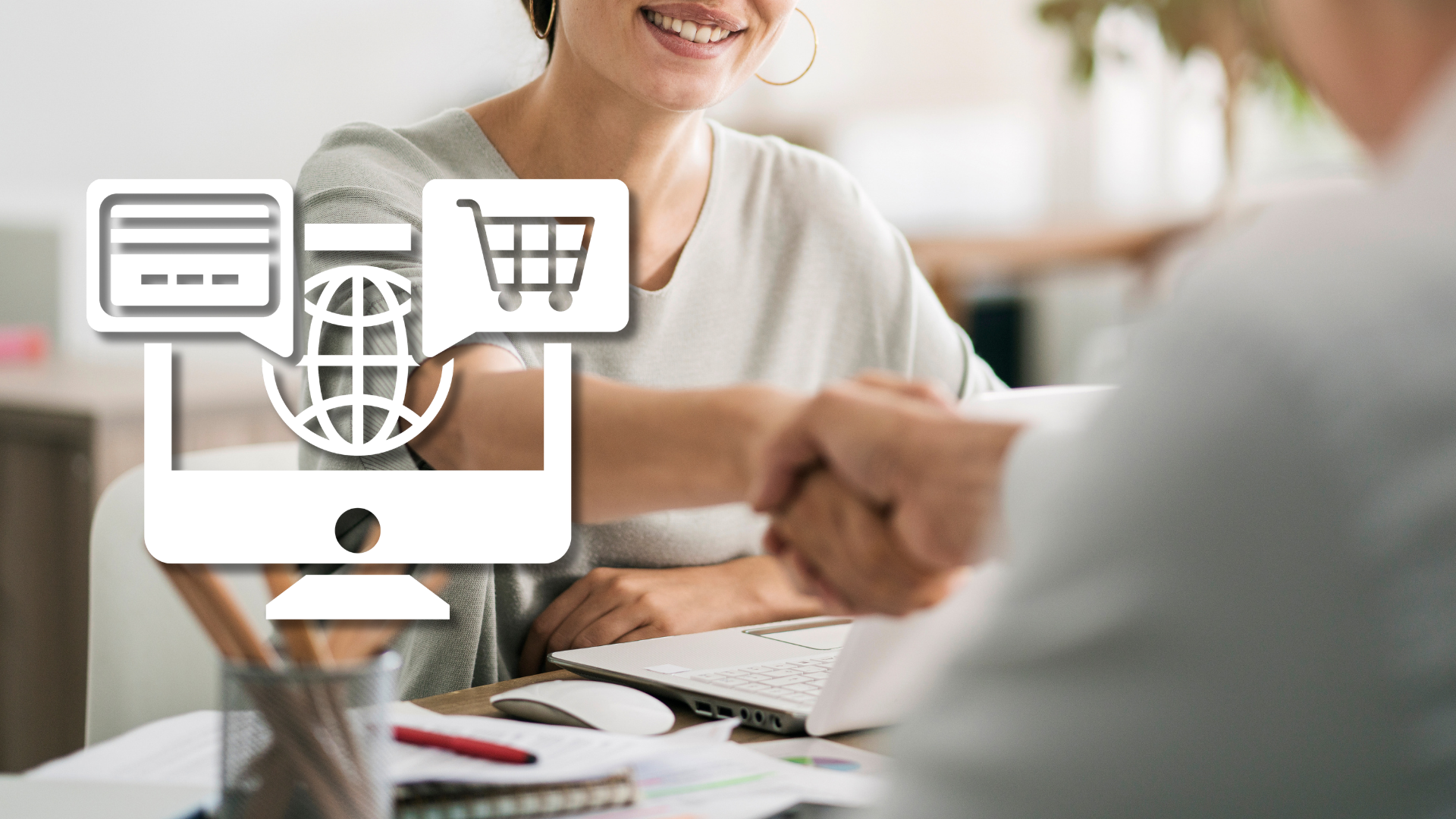 Podanie ruky pri stole s notebookom, vedľa biela ikona internetového obchodu – nábor e-commerce špecialistu na plný úväzok